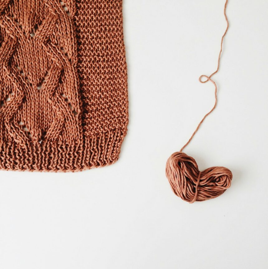 Próbka dzianiny — kwadratowa swatch z warkoczem i kłębek włóczki Kwadratowa próbka dzianiny w stylu stockinette z warkoczem obok kłębka włóczki — próbka obliczeniowa na drutach